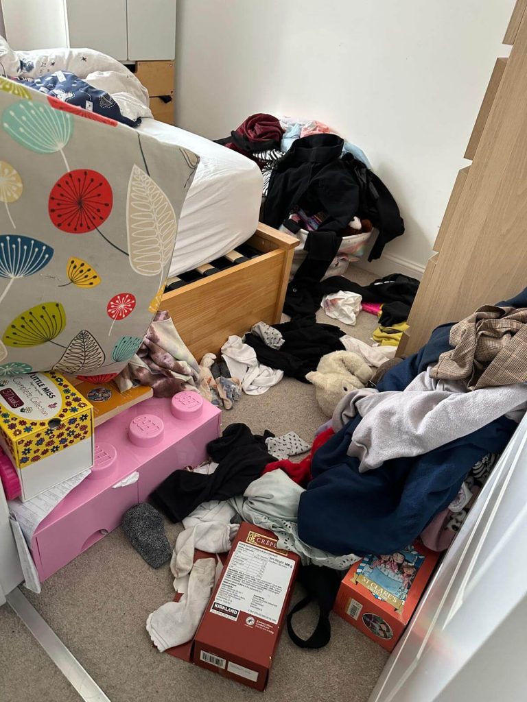 hoarders cleaning job showing bedroom full of clutter with clothing and items on floor and bed, safezone cleaning services