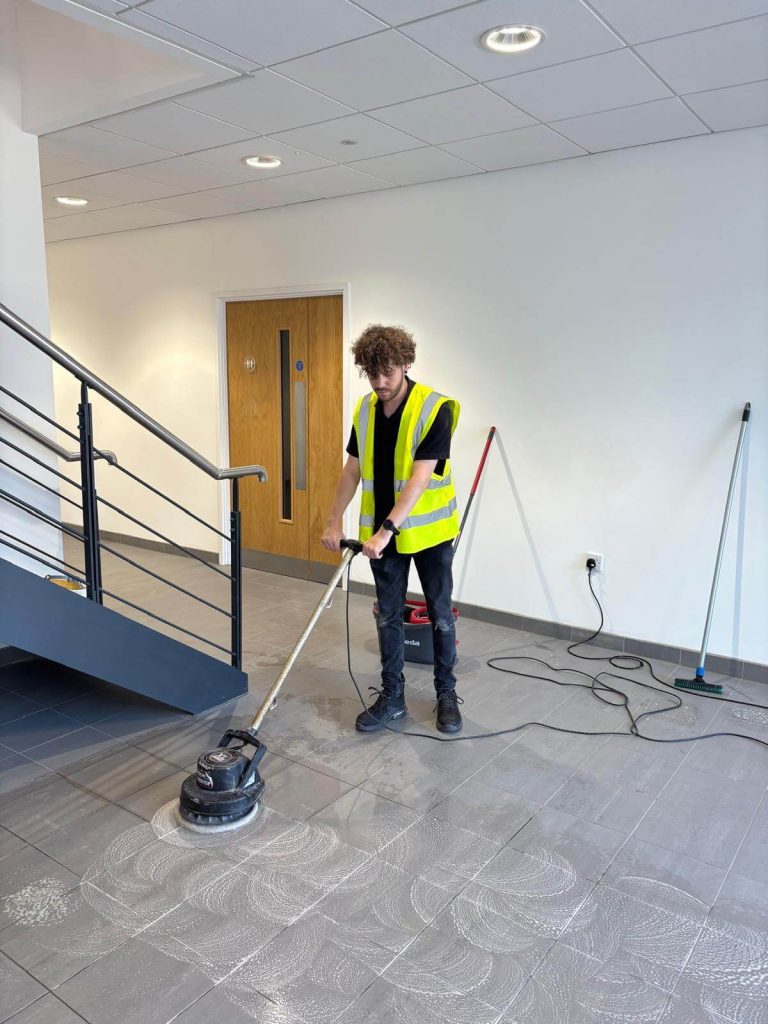 Safezone staff member cleaning up tiles floors in a industrial builders clean